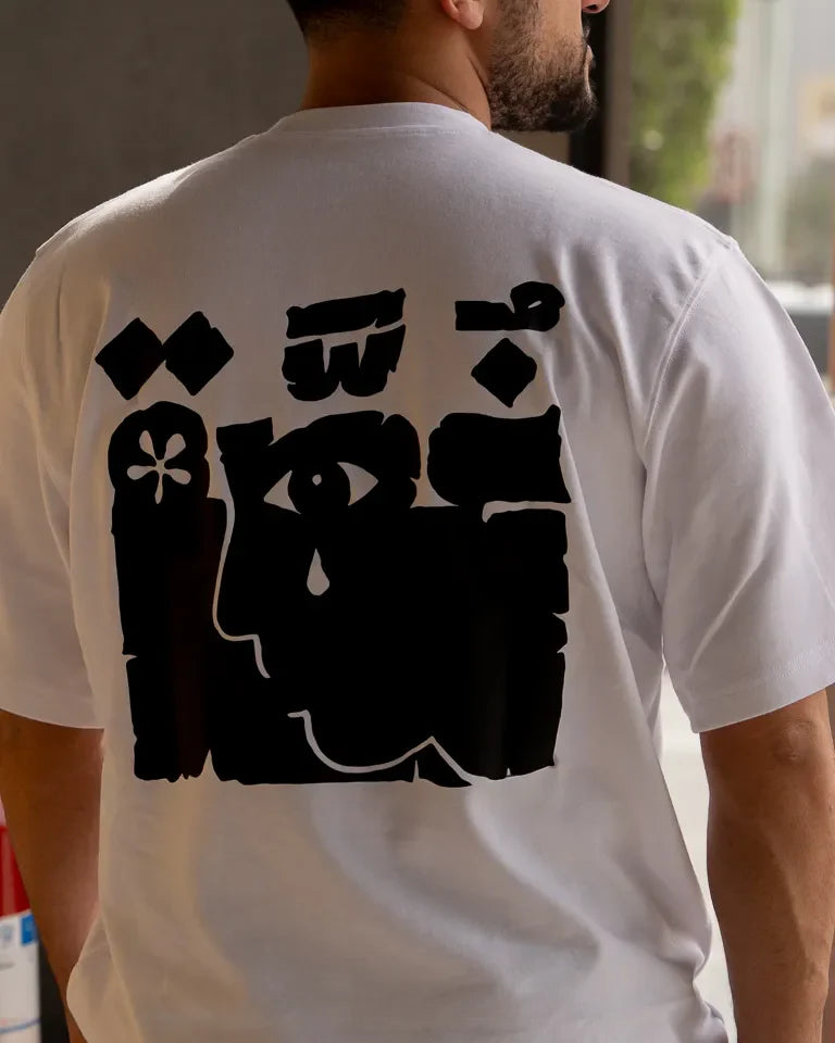 Ghosseh Tee by Ibrahim Zaki — white cotton t-shirt with embroidered Arabic calligraphy expressing layered emotion