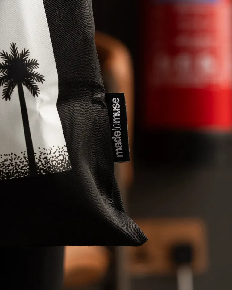 Laymona Travel Tote Bag by Naji Al-Ali LMNBCK — black canvas tote with bold illustrated LMNBCK character design