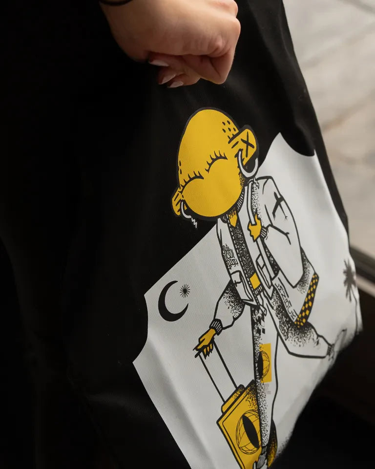 Laymona Travel Tote Bag by Naji Al-Ali LMNBCK — black canvas tote with bold illustrated LMNBCK character design