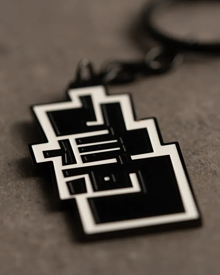 Ishq Keychain by Ibrahim Zaki — enamel keychain with the Arabic word Ishq in dense geometric calligraphy