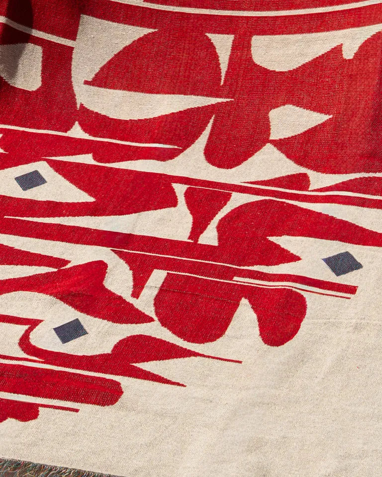 Calligraforms Throw by Wissam Shawkat — woven blanket with bold red Arabic letterforms on neutral ground and fringe edges