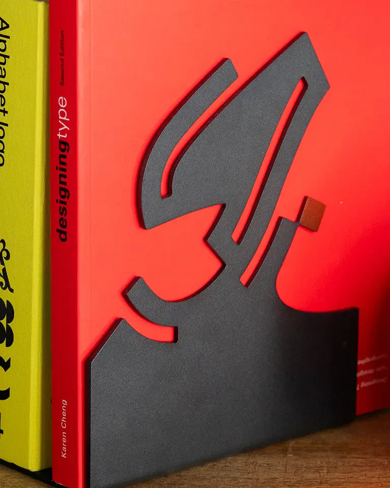 Eternal Bookends by Wissam Shawkat — precision-cut steel bookends with Arabic calligraphy in matte black and red